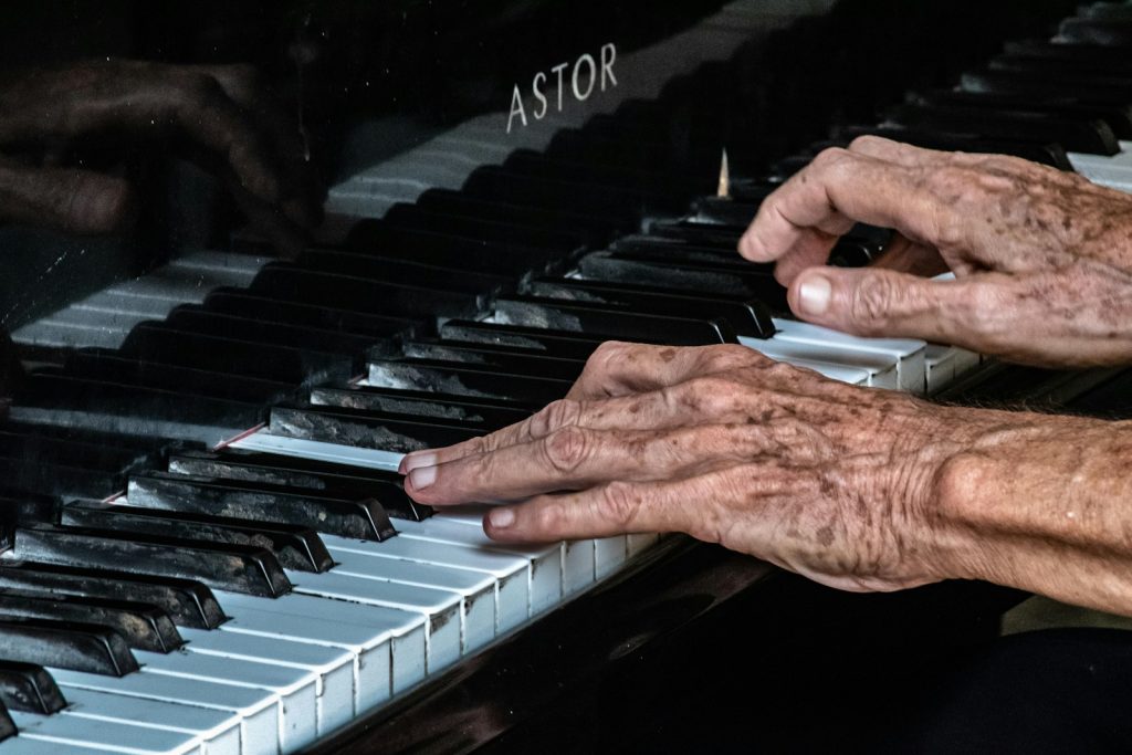 Hände eines alten Menschen spielen Klavier